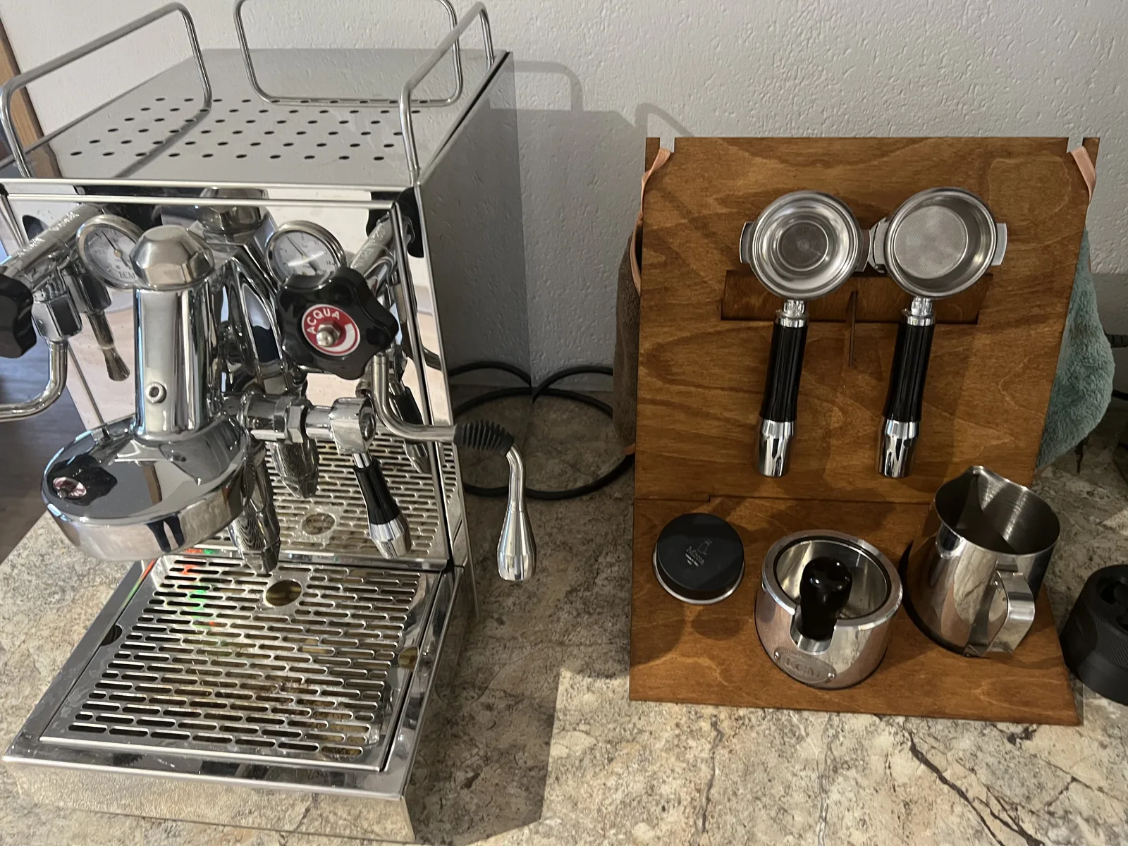 Barista-Station aus dunklem Sperrholz neben der Espressomaschine, mit zwei eingehängten Siebträgern und Milchkanne